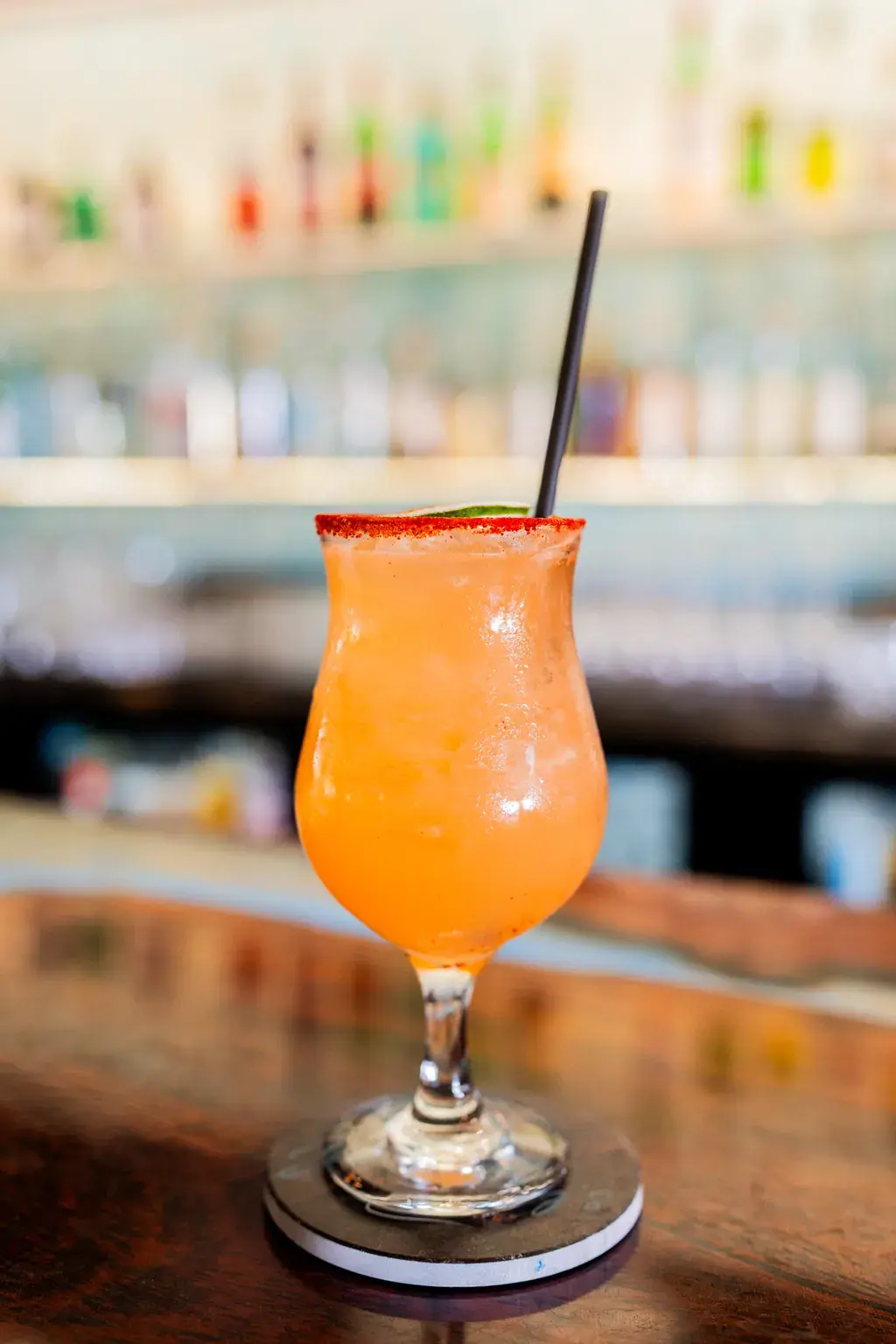 Sunset-hued cocktail with a chili rim and dried orange wheel at the Jackie Rey's Kona bar.