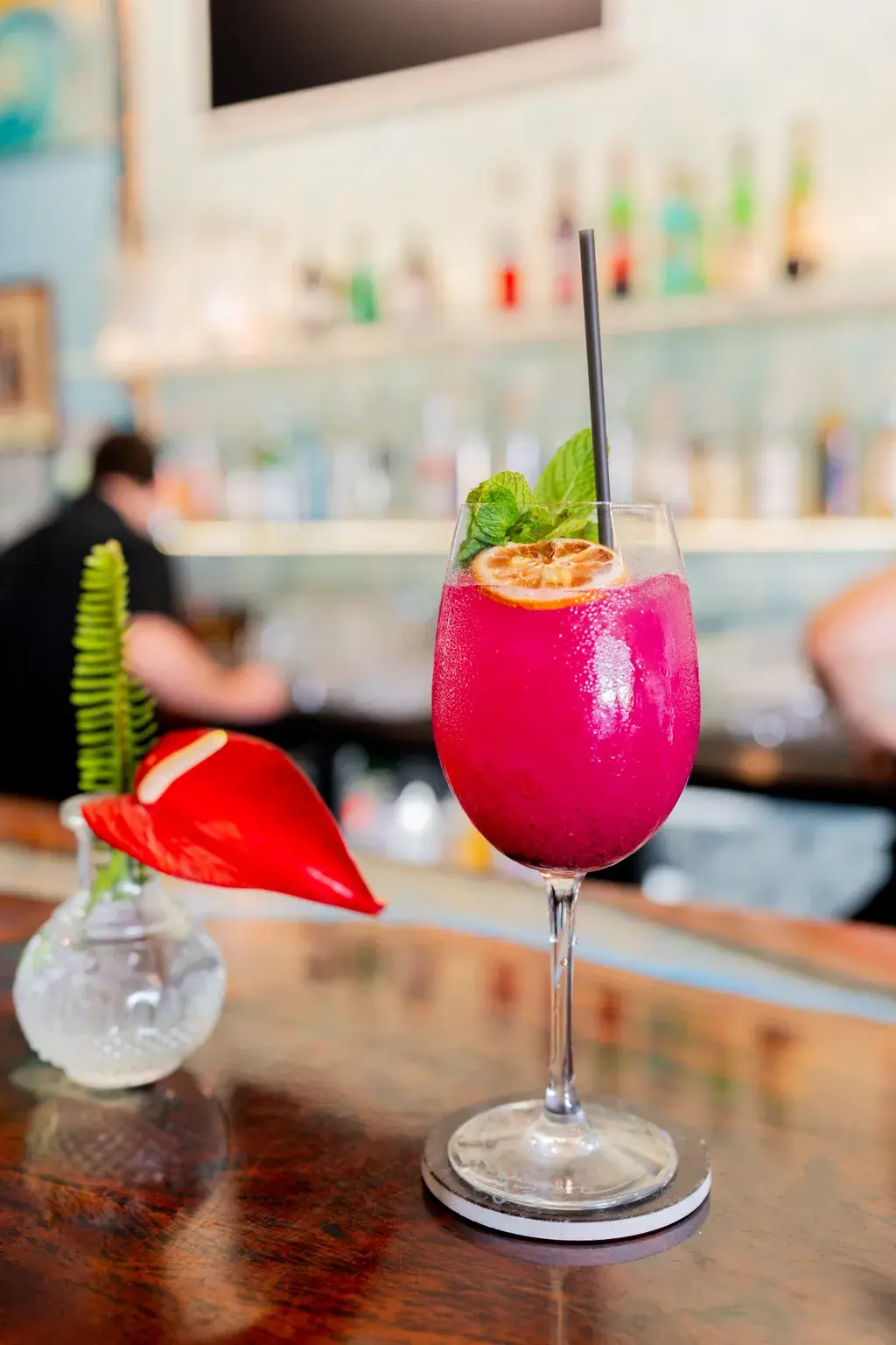 Vivid dragon fruit cocktail beside a red anthurium at Jackie Rey's Kona.