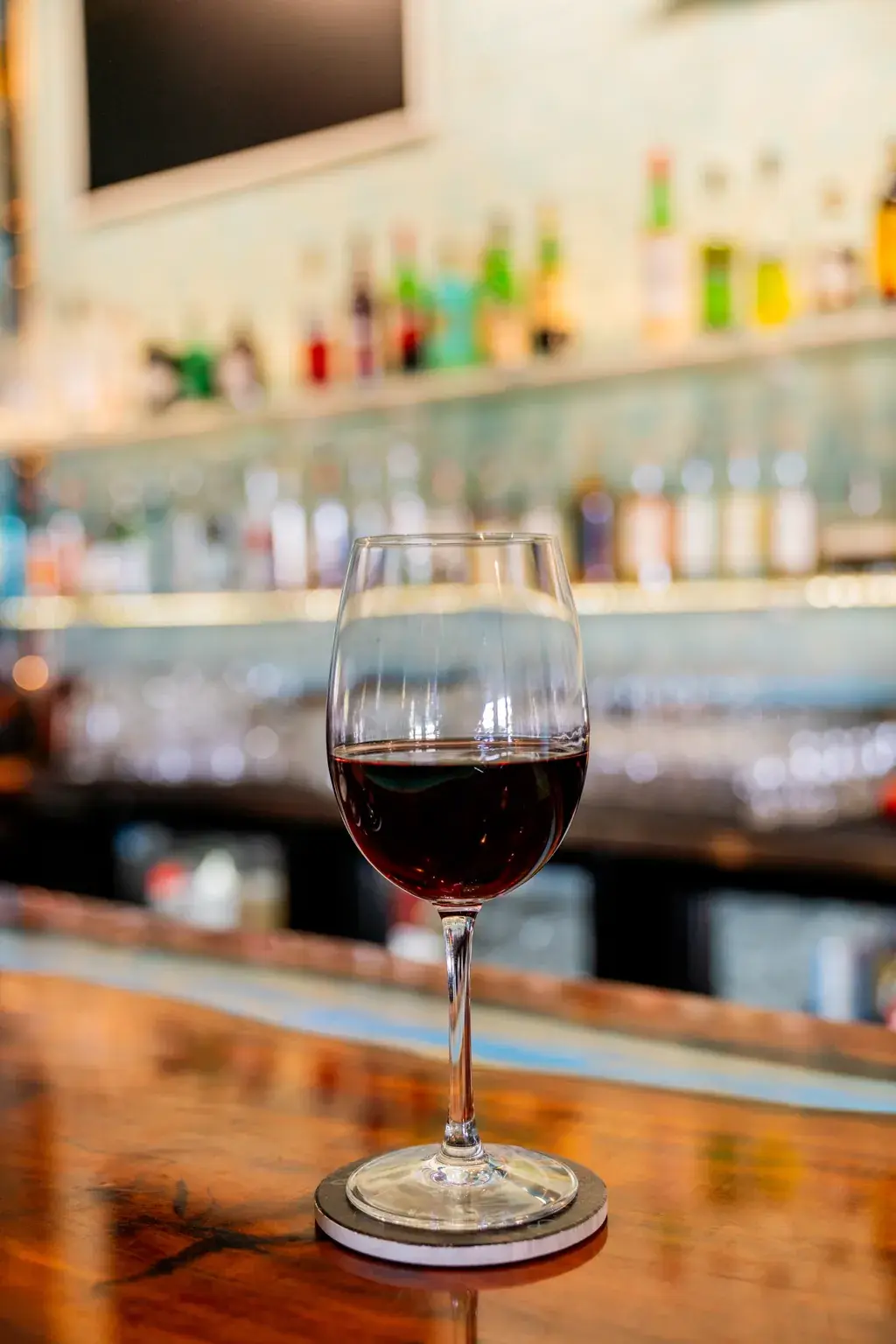 Glass of red wine on the live-edge bar top at Jackie Rey's Kona.