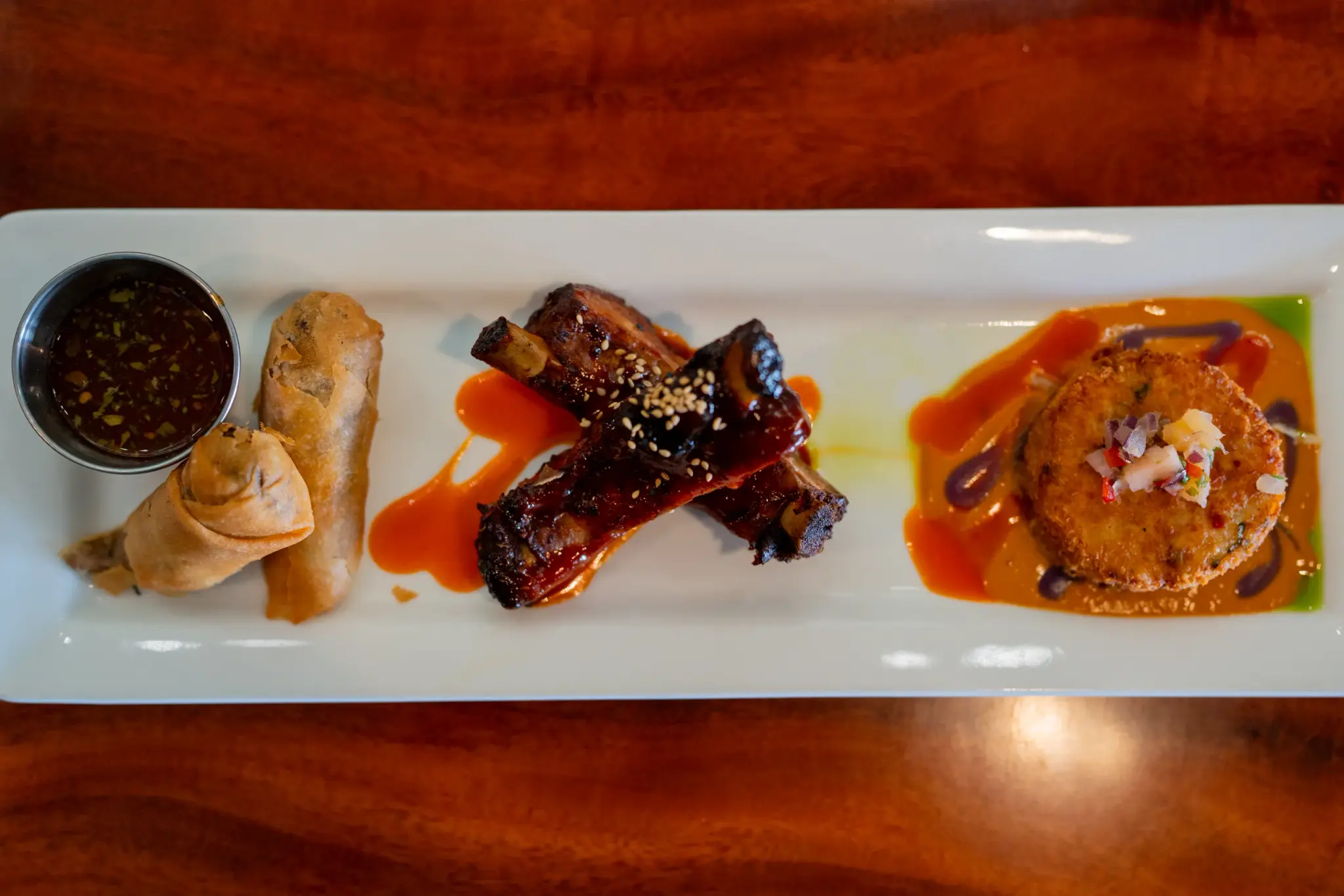 Pūpū Platter at Jackie Rey's Ohana Grill, Spring rolls, crispy pork ribs, crab cake, herb sweet chili, Thai curry, pineapple relish.
