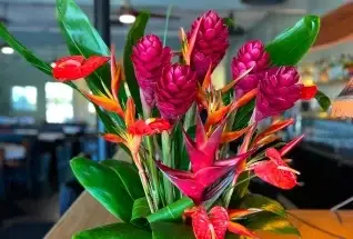 A tropical ginger and heliconia arrangement by Wailani Flower Co on a table at Jackie Rey's Kona.