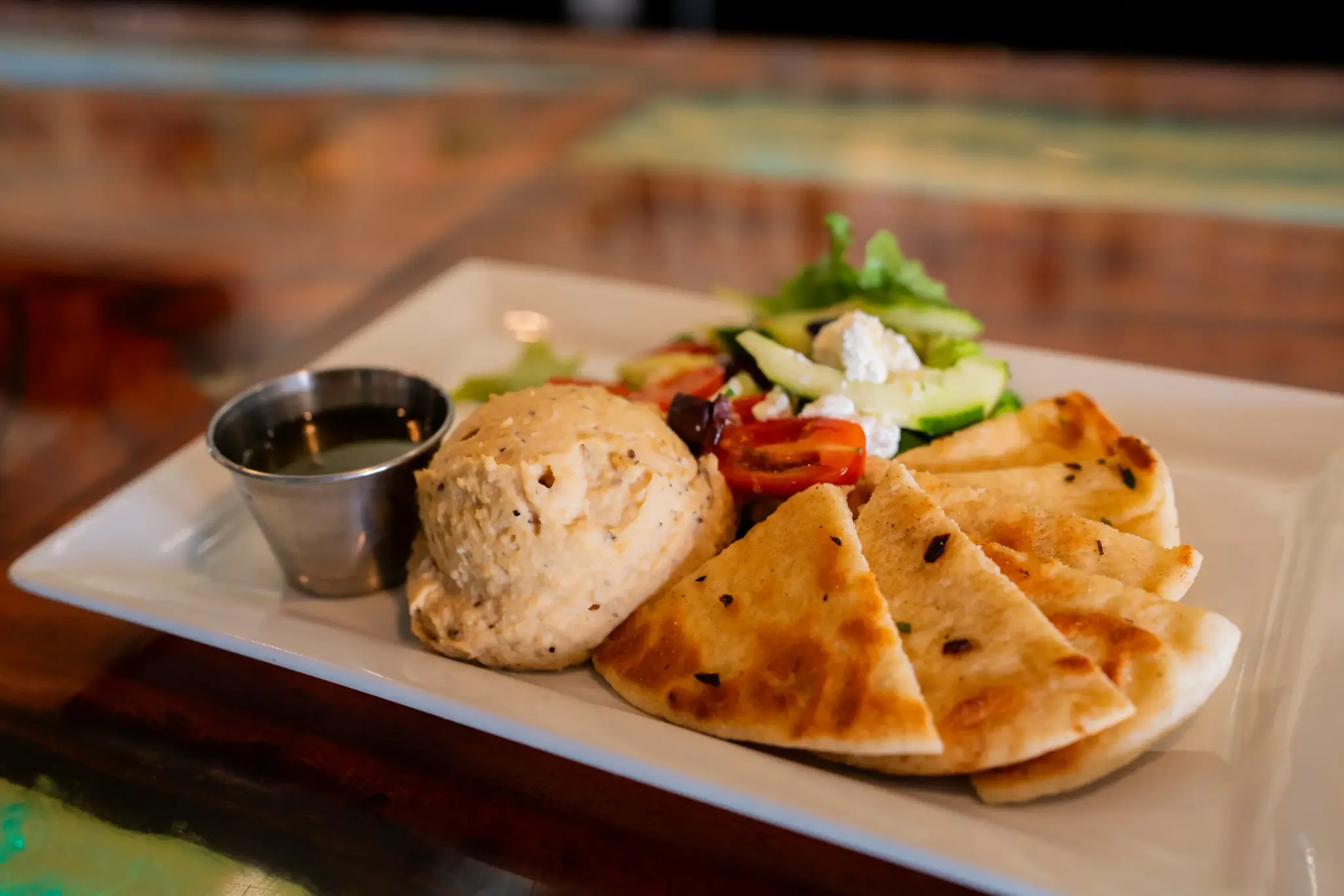 Mediterranean Hummus at Jackie Rey's Ohana Grill, Housemade hummus, olive oil, olives, tomatoes, cucumber, feta, pita bread.