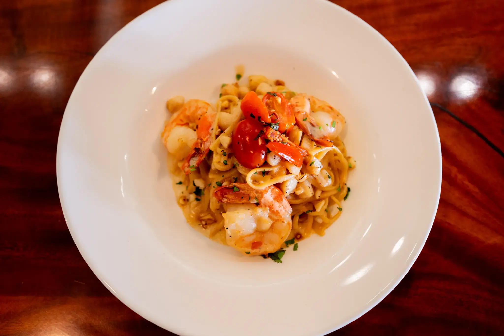 Seafood Linguini at Jackie Rey's Ohana Grill, Bay scallops, jumbo shrimp, coconut garlic cream, basil-tomato relish, toasted mac nuts, parmesan.