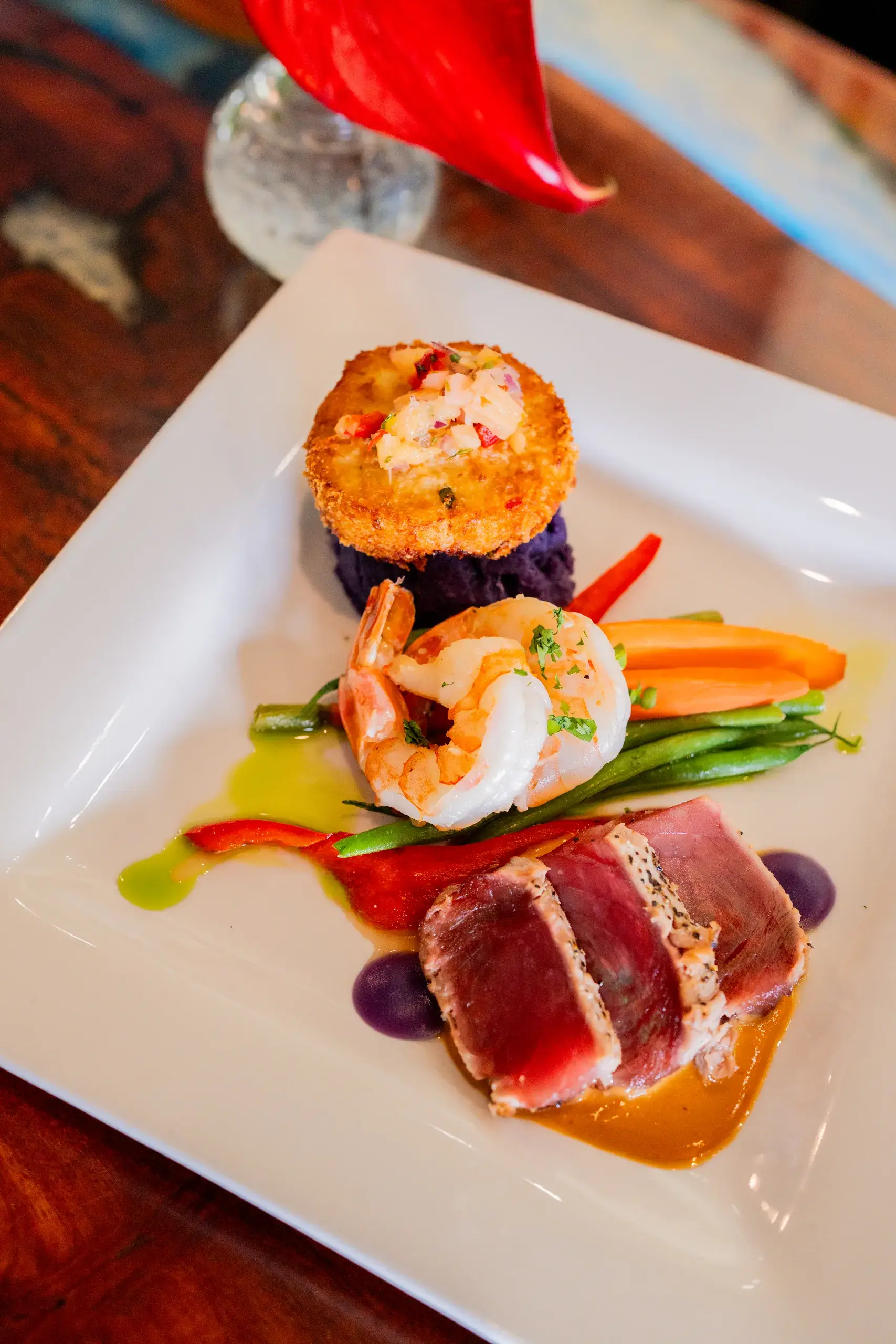 Seafood Trio at Jackie Rey's Ohana Grill, Seared ahi, garlic jumbo shrimp, crab cake, garlic vegetables, Molokai purple mash, coconut red Thai curry, Molokai purple potato emulsion, pineapple relish.